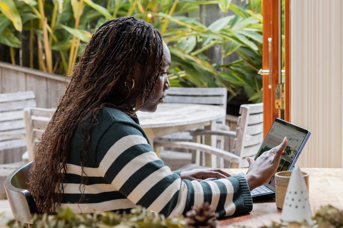Profissional usando o tablet numa mesa cercada de plantas